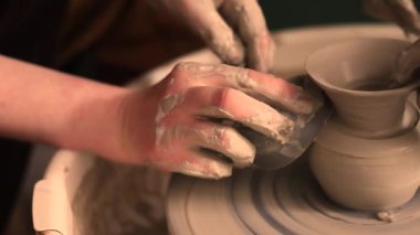 Zanaatkar bir stüdyoda çömlek çarkında çamurla çalışan ellerin yakın çekimi. Yaratıcı hobi, aktif seramik sanat ve özenli el işçiliği. Yüksek kalite 4k görüntü