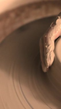 Zanaatkar bir stüdyoda çömlek çarkında çamurla çalışan ellerin yakın çekimi. Yaratıcı hobi, aktif seramik sanat ve özenli el işçiliği. Yüksek kalite 4k görüntü