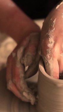 Zanaatkar bir stüdyoda çömlek çarkında çamurla çalışan ellerin yakın çekimi. Yaratıcı hobi, aktif seramik sanat ve özenli el işçiliği. Yüksek kalite 4k görüntü