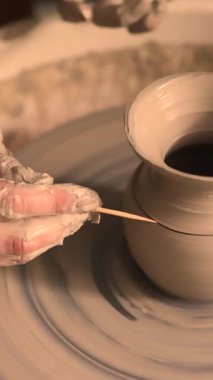 Zanaatkar bir stüdyoda çömlek çarkında çamurla çalışan ellerin yakın çekimi. Yaratıcı hobi, aktif seramik sanat ve özenli el işçiliği. Yüksek kalite 4k görüntü