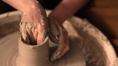 Zanaatkar bir stüdyoda çömlek çarkında çamurla çalışan ellerin yakın çekimi. Yaratıcı hobi, aktif seramik sanat ve özenli el işçiliği. Yüksek kalite 4k görüntü