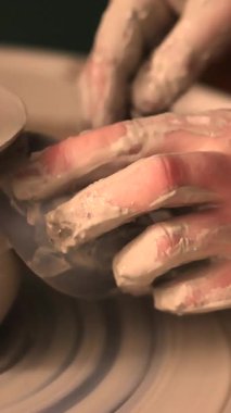 Zanaatkar bir stüdyoda çömlek çarkında çamurla çalışan ellerin yakın çekimi. Yaratıcı hobi, aktif seramik sanat ve özenli el işçiliği. Yüksek kalite 4k görüntü