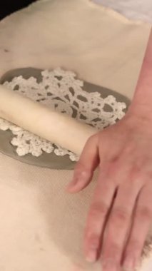 Çömlek atölyesinde el yapımı seramik Noel süslemeleri. Balçığa şenlik desenleri yerleştirmek için kumaş kar tanesi şablonu ve merdane kullanılıyor. Yaratıcı ve samimi bir tatil hazırlığı. Yüksek kalite 4k görüntü