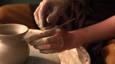 Zanaatkar bir stüdyoda çömlek çarkında çamurla çalışan ellerin yakın çekimi. Yaratıcı hobi, aktif seramik sanat ve özenli el işçiliği. Yüksek kalite 4k görüntü