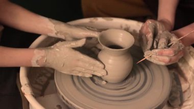 Zanaatkar bir stüdyoda çömlek çarkında çamurla çalışan ellerin yakın çekimi. Yaratıcı hobi, aktif seramik sanat ve özenli el işçiliği. Yüksek kalite 4k görüntü