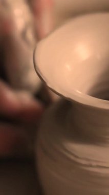 Zanaatkar bir stüdyoda çömlek çarkında çamurla çalışan ellerin yakın çekimi. Yaratıcı hobi, aktif seramik sanat ve özenli el işçiliği. Yüksek kalite 4k görüntü