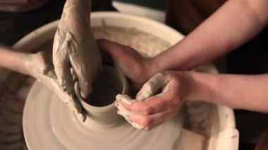 Zanaatkar bir stüdyoda çömlek çarkında çamurla çalışan ellerin yakın çekimi. Yaratıcı hobi, aktif seramik sanat ve özenli el işçiliği. Yüksek kalite 4k görüntü