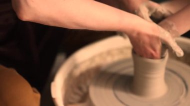 Zanaatkar bir stüdyoda çömlek çarkında çamurla çalışan ellerin yakın çekimi. Yaratıcı hobi, aktif seramik sanat ve özenli el işçiliği. Yüksek kalite 4k görüntü
