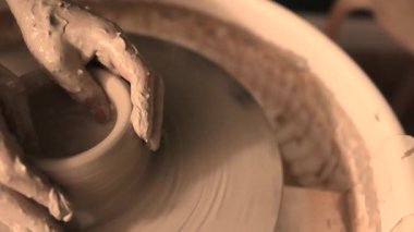Zanaatkar bir stüdyoda çömlek çarkında çamurla çalışan ellerin yakın çekimi. Yaratıcı hobi, aktif seramik sanat ve özenli el işçiliği. Yüksek kalite 4k görüntü