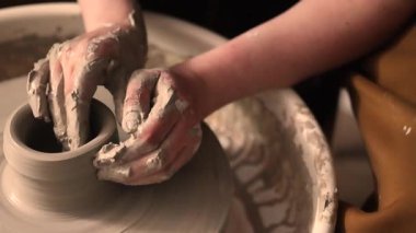 Zanaatkar bir stüdyoda çömlek çarkında çamurla çalışan ellerin yakın çekimi. Yaratıcı hobi, aktif seramik sanat ve özenli el işçiliği. Yüksek kalite 4k görüntü