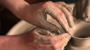 Zanaatkar bir stüdyoda çömlek çarkında çamurla çalışan ellerin yakın çekimi. Yaratıcı hobi, aktif seramik sanat ve özenli el işçiliği. Yüksek kalite 4k görüntü