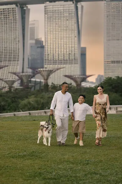 Singapur 'da Marina Bay Sands yakınlarında gülümseyen Asyalı baba, Doğu Avrupalı anne, çocuk ve köpekli mutlu melez bir aile. Kentsel tropikal şehirde keyifli bir açık hava anı. Yüksek kalite fotoğraf