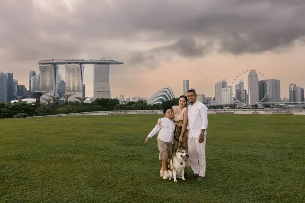 Singapur 'da Marina Bay Sands yakınlarında gülümseyen Asyalı baba, Doğu Avrupalı anne, çocuk ve köpekli mutlu melez bir aile. Kentsel tropikal şehirde keyifli bir açık hava anı. Yüksek kalite fotoğraf