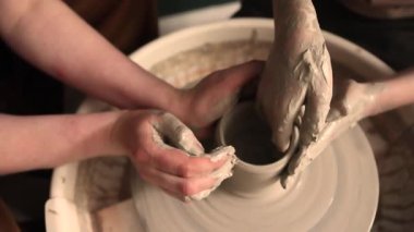 Zanaatkar bir stüdyoda çömlek çarkında çamurla çalışan ellerin yakın çekimi. Yaratıcı hobi, aktif seramik sanat ve özenli el işçiliği. Yüksek kalite 4k görüntü