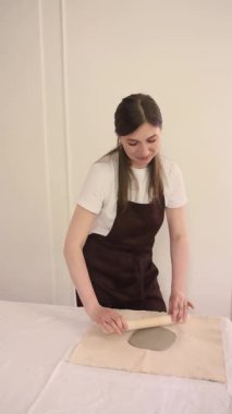  Sıcak çömlek atölyesinde kil yuvarlarken önlüklü gülümseyen kadın çömlekçi. Neşeli sanatsal hobi. Yüksek kalite 4k görüntü