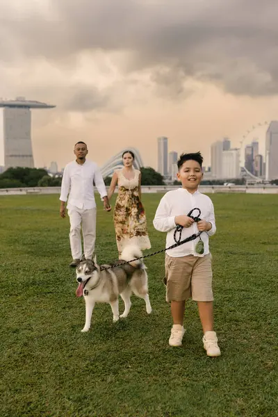 Singapur 'da Marina Bay Sands yakınlarında gülümseyen Asyalı baba, Doğu Avrupalı anne, çocuk ve köpekli mutlu melez bir aile. Kentsel tropikal şehirde keyifli bir açık hava anı. Yüksek kalite fotoğraf