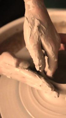 Zanaatkar bir stüdyoda çömlek çarkında çamurla çalışan ellerin yakın çekimi. Yaratıcı hobi, aktif seramik sanat ve özenli el işçiliği. Yüksek kalite 4k görüntü