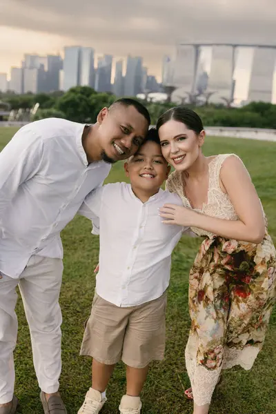 Singapur 'da eğlenen üç kişilik mutlu uluslararası aile. Asyalı baba, Doğu Avrupalı anne ve Marina Körfezi Kumları 'nın ve şehir gökdelenlerinin önünde gülümseyen 7 yaşındaki çocukları. Yüksek kalite fotoğraf