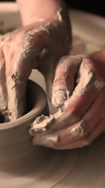 Zanaatkar bir stüdyoda çömlek çarkında çamurla çalışan ellerin yakın çekimi. Yaratıcı hobi, aktif seramik sanat ve özenli el işçiliği. Yüksek kalite 4k görüntü