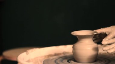 Zanaatkar bir stüdyoda çömlek çarkında çamurla çalışan ellerin yakın çekimi. Yaratıcı hobi, aktif seramik sanat ve özenli el işçiliği. Yüksek kalite 4k görüntü