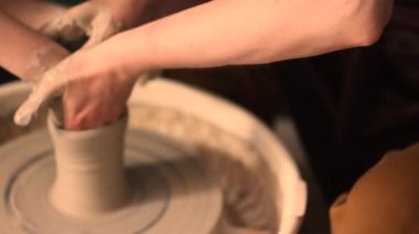 Zanaatkar bir stüdyoda çömlek çarkında çamurla çalışan ellerin yakın çekimi. Yaratıcı hobi, aktif seramik sanat ve özenli el işçiliği. Yüksek kalite 4k görüntü