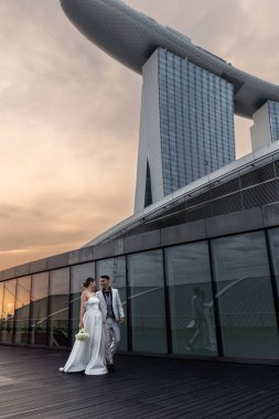 Gelin ve damat, Singapur şehrinin arka planına karşı. Güneşin doğuşu düğün fotoğrafı. - Evet. Yüksek kalite fotoğraf