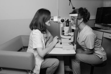 Oftalmolojist, klinikteki hastaların gözlerini profesyonel teşhis cihazıyla muayene ediyor. Göz testi yapılıyor. Klinik ortamlarda vizyon taraması ve sağlık kontrolü.