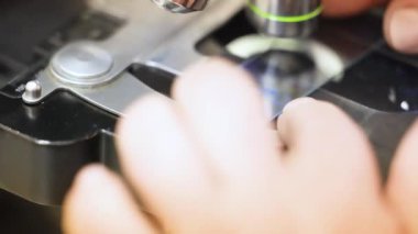 Tıbbi elektronik mikroskobun detaylı yakın çekimleri, bir sağlık ortamında laboratuvar analizi ve tanı araştırmasında kullanılan cam kaydırma üzerine odaklanmıştır.