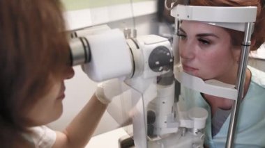 Oftalmolojist, klinikteki hastaların gözlerini profesyonel teşhis cihazıyla muayene ediyor. Göz testi yapılıyor. Klinik ortamlarda vizyon taraması ve sağlık kontrolü.