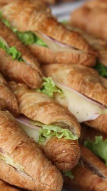 Çok sayıda kruvasan, jambon, peynir ve tabakta servis edilen yeşillikler. Yüksek kalite fotoğraf