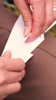 Adam dışarıda, gün ışığında dizinin üzerinde kağıt uçak monte ediyor. Yüksek kalite 4k görüntü