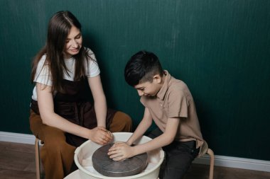 Kafkas anne ve oğlu hobi seramik stüdyosunda çömlek tekerinde çalışıyor. Eller kilde, birlikte kil çömlek yapıyorlar. Aile mesleği ve el yapımı seramik çalışmalarla yaratıcılık bağı