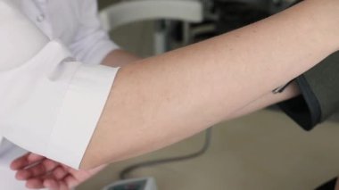 Doktorun tıbbi cihaz kullanarak kan basıncını ölçtüğü yakın plan, eller görünür. Yüksek kalite 4k görüntü