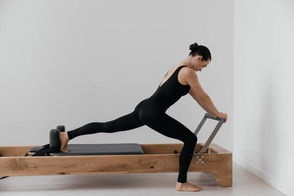 Pilates reformer training machine. sporty woman exercising gym. High quality photo
