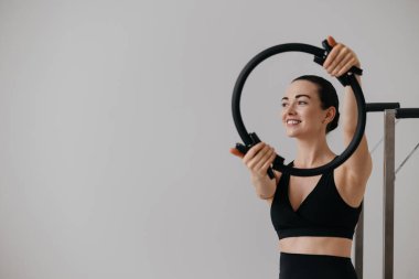 Pilates yaparken elinde pilates yüzüğü tutan gülümseyen genç bir kadın. Güç ve denge için pilates çemberiyle spor. Yüksek kalite fotoğraf