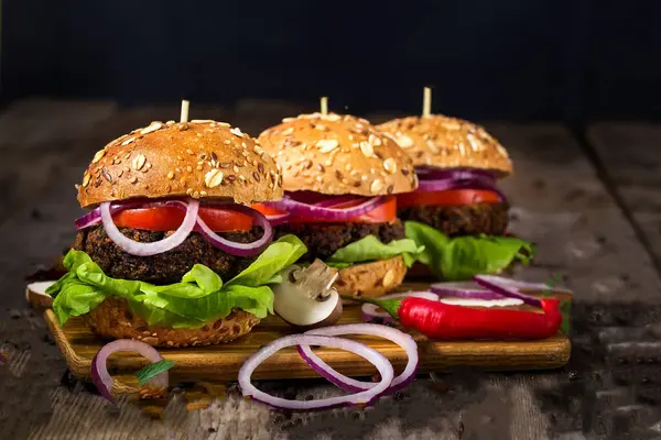 Selective image of burger with onion, mint, green parsley and souce on black background