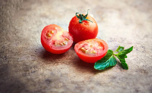 selective image of red tomatoes with leaf. Whole tomato fruit and sliced tomato on wooden table