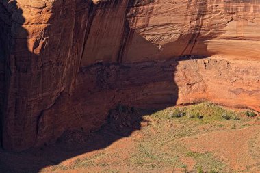 Arizona, Chelle Kanyonu 'ndaki harabeler ve kayalar, kanyon zeminine yeşil bitkiler serpiştiriyor..