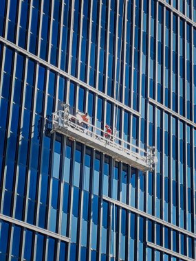 Yüksek katlı bir pencere temizleme platformunda çalışanlar Phoenix, Arizona 'daki pencerelere film uyguluyorlar..