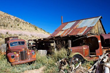 Eski paslı bir araba ve kamyon terk edilmiş bir kulübenin önünde. Jerome, Arizona.