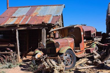 Paslı metal çatılı eski bir barakanın önünde paslanmış eski bir tanker. Jerome, Arizona.