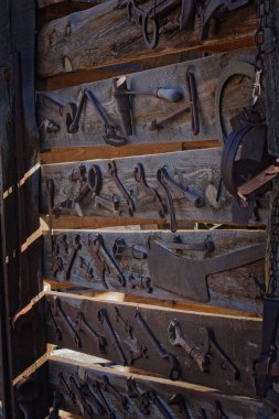 Eski, yıpranmış tahta duvarlara bağlı eski aletler. Jerome, Arizona.