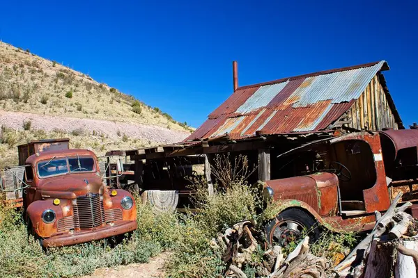 Eski paslı bir araba ve kamyon terk edilmiş bir kulübenin önünde. Jerome, Arizona.