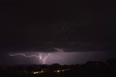 Arizona 'da bir fırtına sırasında yere düşen yıldırımlar. Şehir ışıkları ön planda..