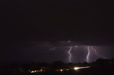 Arizona 'da bir fırtına sırasında yere düşen yıldırımlar. Şehir ışıkları ön planda..