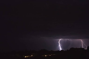 Arizona 'da bir fırtına sırasında yere düşen yıldırımlar. Şehir ışıkları ön planda..