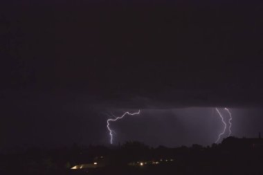 Arizona 'da bir fırtına sırasında yere düşen yıldırımlar. Şehir ışıkları ön planda..