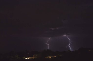 Arizona 'da bir fırtına sırasında yere düşen yıldırımlar. Şehir ışıkları ön planda..