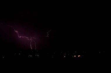 Arizona 'da bir fırtına sırasında yere düşen yıldırımlar. Şehir ışıkları ön planda..