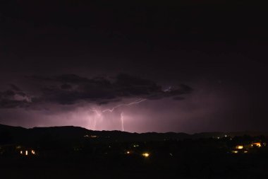 Arizona 'da bir fırtına sırasında yıldırım düştü. Şehir ışıkları ön planda..